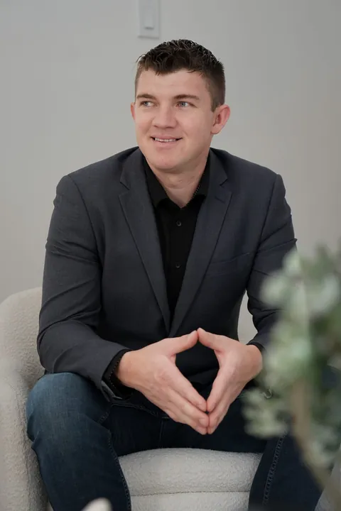 Abe Thiessen, seated in an armchair, smiling to the side