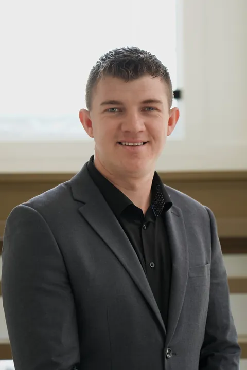Abe Thiessen, in a charcoal blazer by a bright window