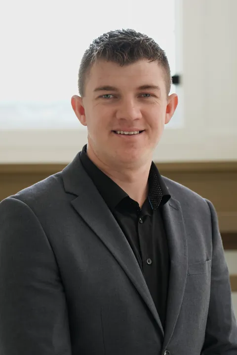 Abe Thiessen, standing by a bright window, smiling